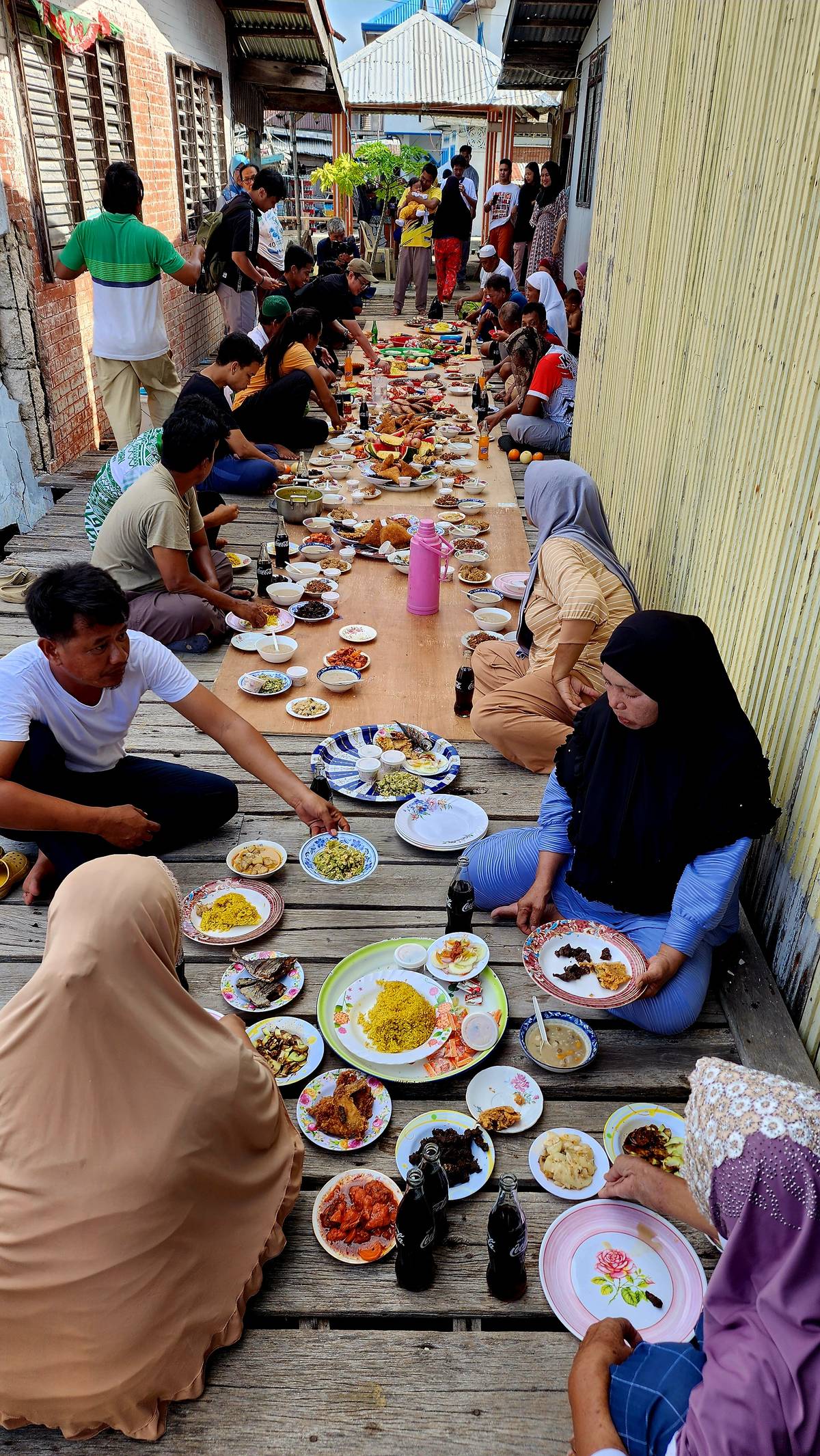 A large family and their friends and neighbors having a feast, and anyone who passes by is invited to join.